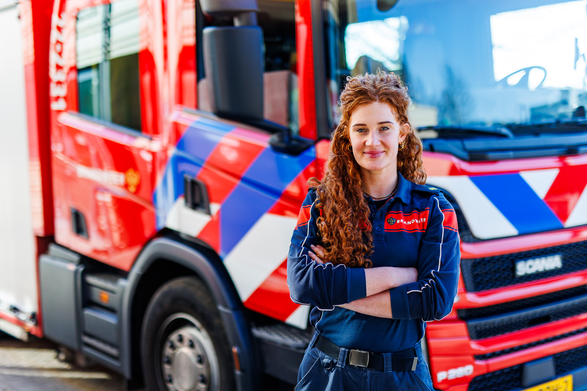 Emy Bluekens in brandweeruniform voor een brandweerauto